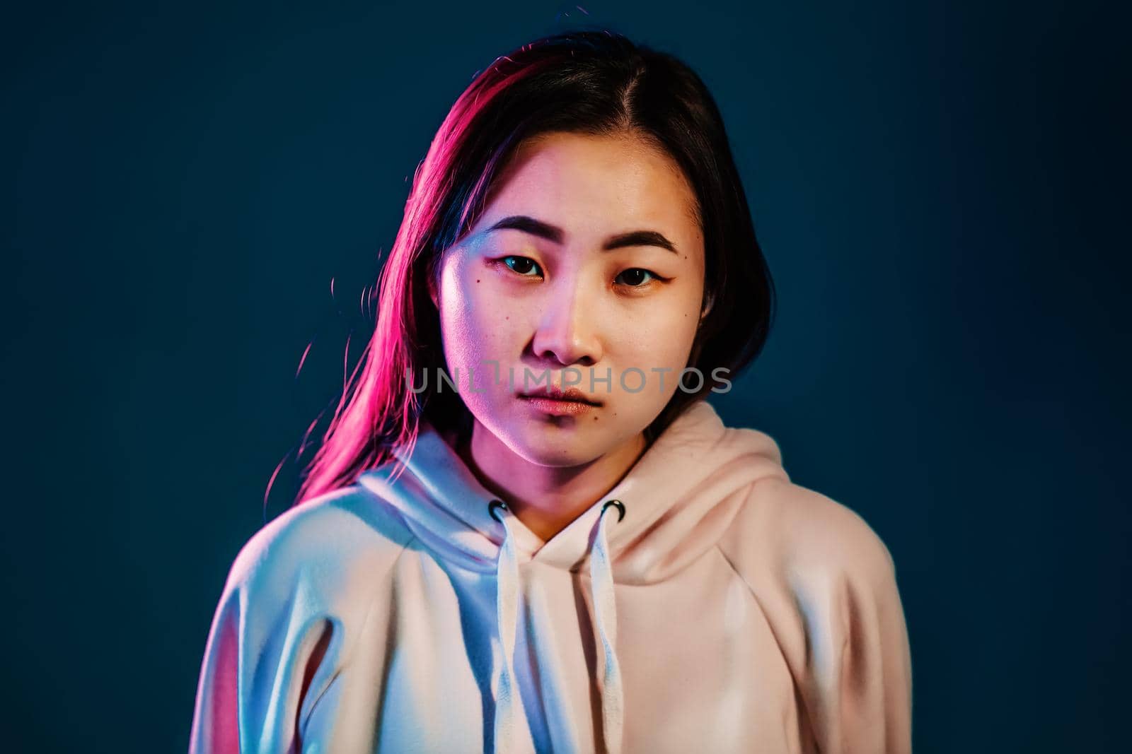 Close up portrait of millennial pretty korean woman with long hairstyle with neon light. Hipster teenager in studio.