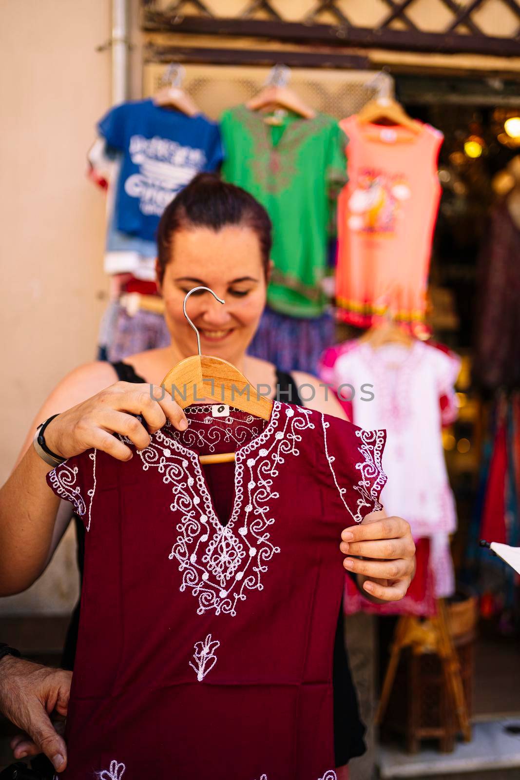 A young woman showing clothes in a street market. Stock photography.