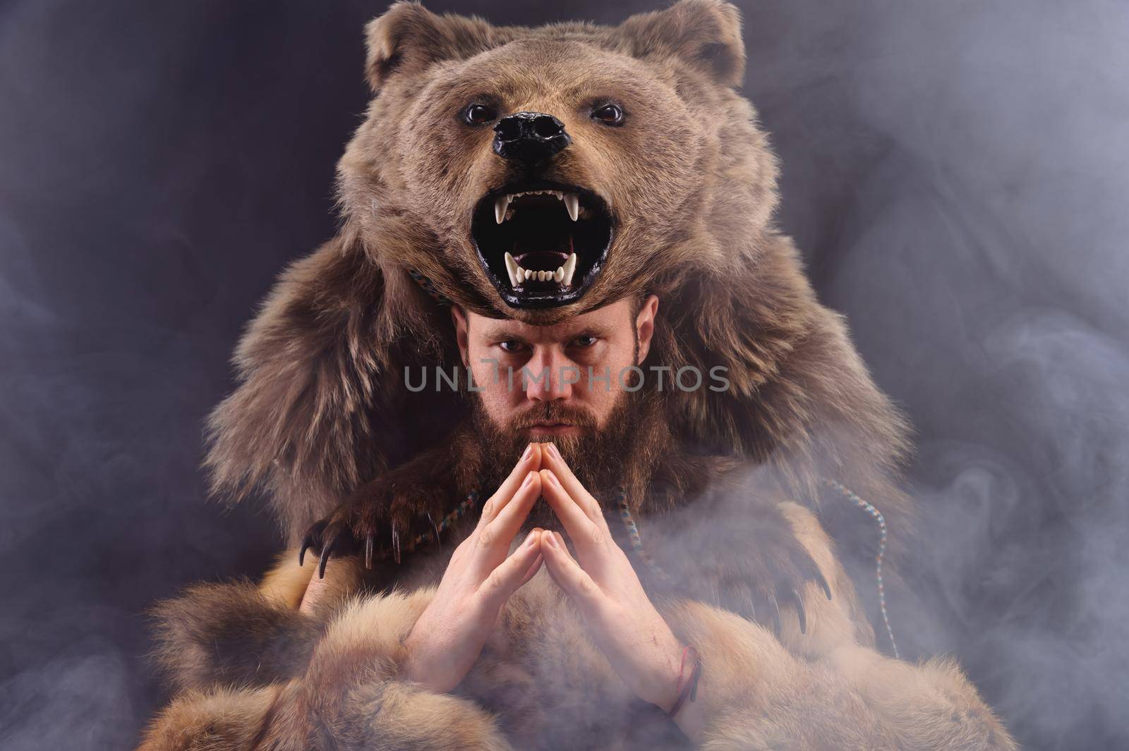 A traditional medieval bearded man dressed as an animal-bear, a symbol of power, strength and greatness. studio shot cosplay.