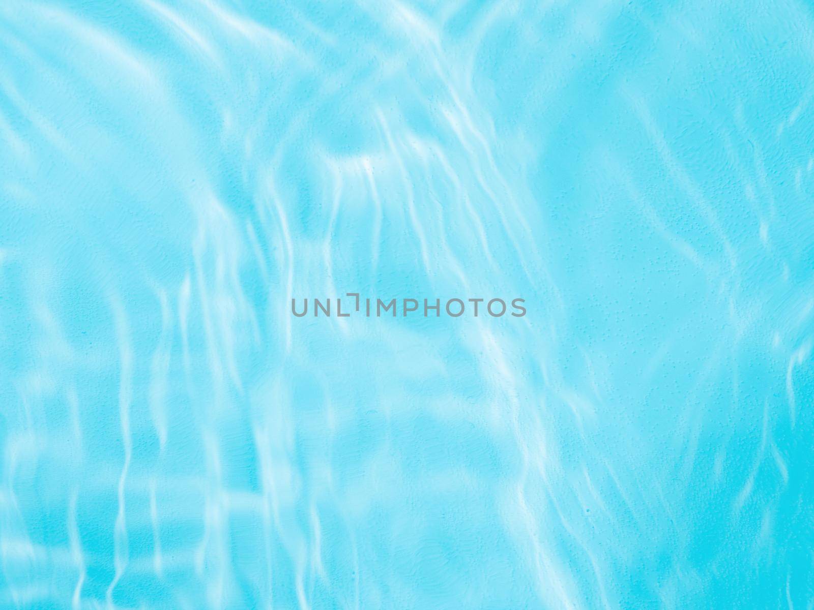 Ripple water texture on blue pool background. Shadow of water on sunlight. Mockup for product, spa or travel background. Marble blue water surface as wallpaper background