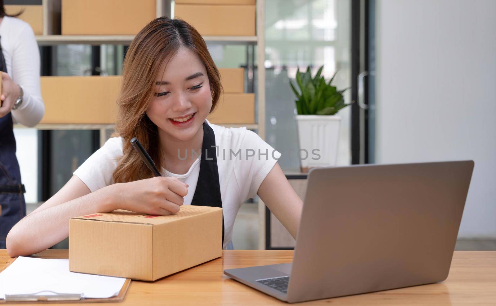 Portrait of Asian young woman SME working with a box at home the workplace.start-up small business owner, small business entrepreneur SME or freelance business online and delivery concept..