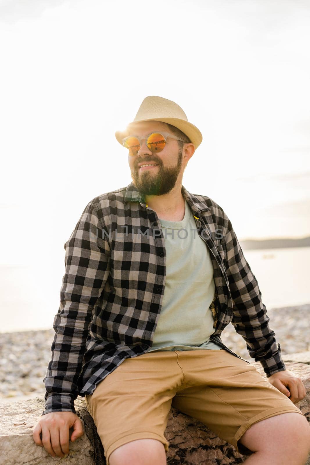 Handsome and confident. Outdoor portrait of smiling man wearing hat and sunglasses on beach. Holidays travel and summer tourism by Satura86