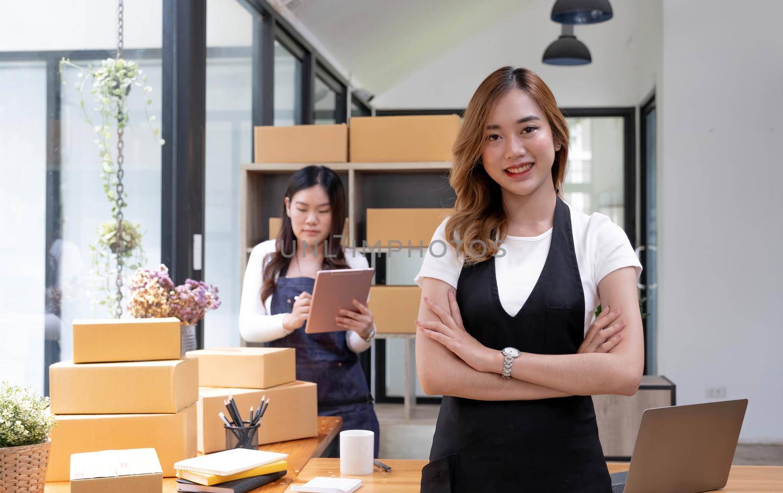 Portrait of Asian young woman SME working with a box at home the workplace.start-up small business owner, small business entrepreneur SME or freelance business online and delivery concept. by wichayada