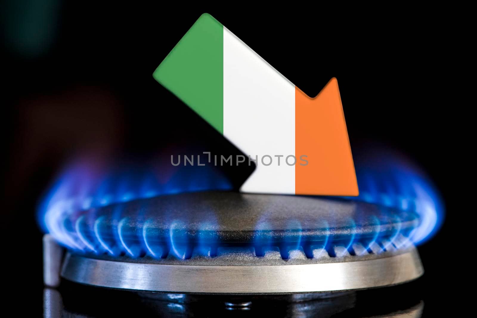 Decreased gas supplies in Ireland. A gas stove with a burning flame and an arrow in the colors of the Ireland flag pointing down. Concept of crisis in winter and lack of natural gas. Heating season