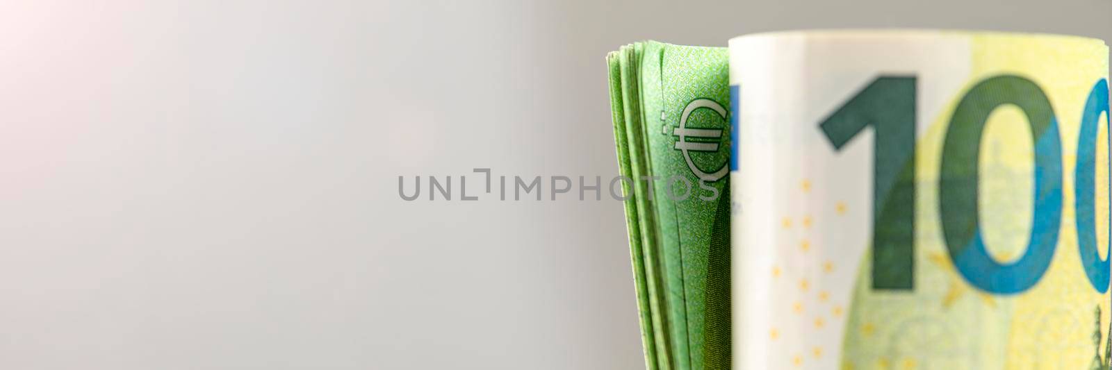 Roll of money. Roll of 100 euro banknotes. Euro banknotes rolled up on a gray background. The concept of financial assistance, real estate purchase, loan or insurance payment. by SERSOL