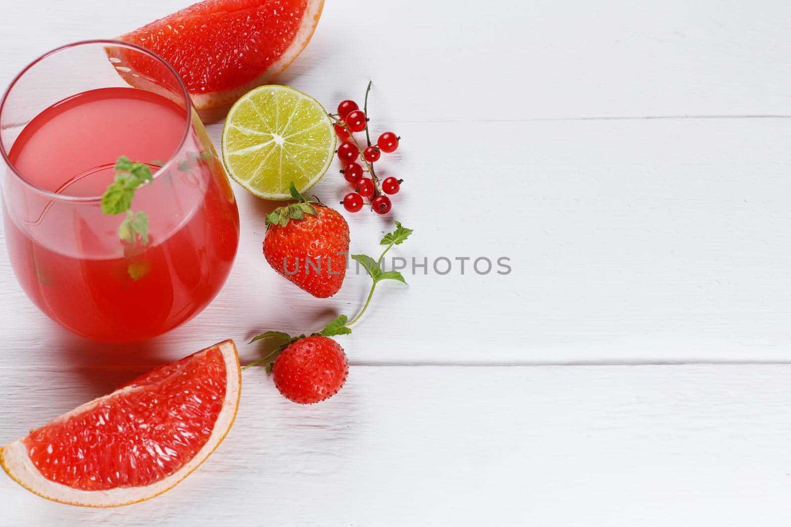 Fresh grapefruit juice in a glass with grapefruit slices, lime and mint on a wooden background. Copy space, selective focus by lara29