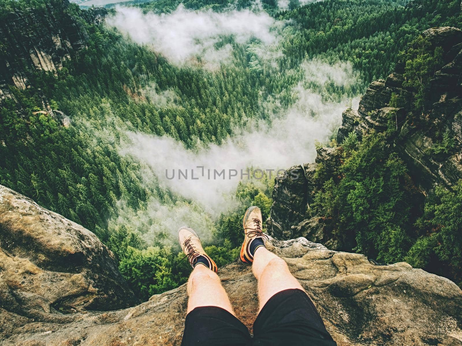 Hiker legs hiking in fall nature. Guy just relax on mountain top  by rdonar2