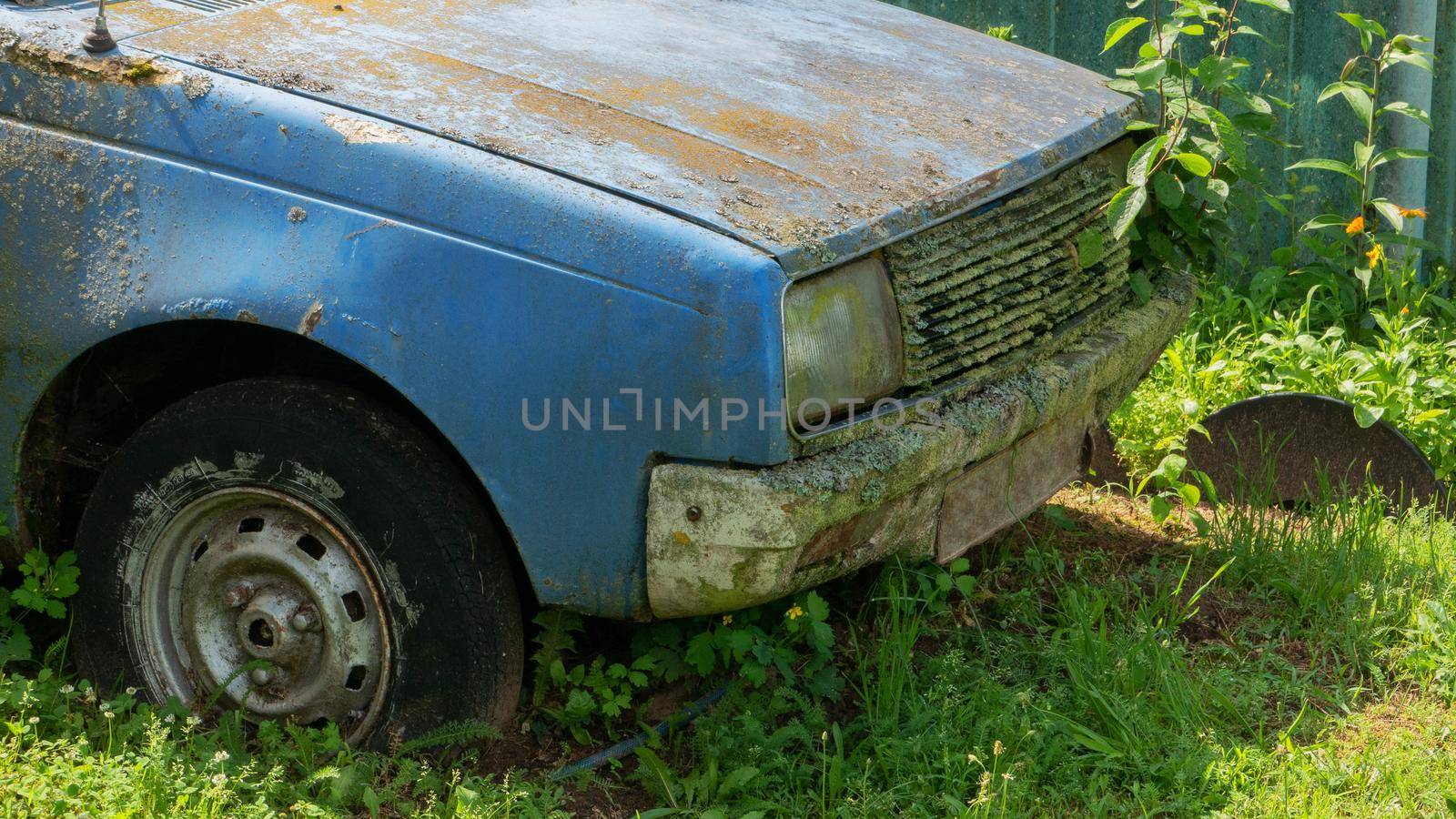 broken car close-up view. Fragment of the front part of the car of an abandoned faulty car. The front of an abandoned car on the green grass.