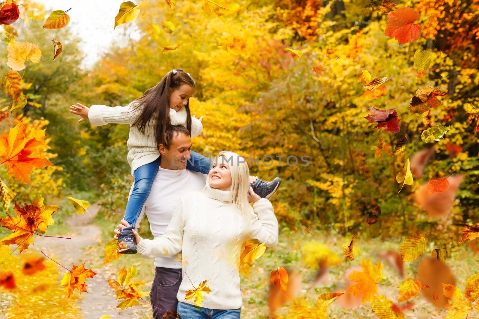 family, childhood, season and people concept - happy family playing with autumn leaves in park by Andelov13