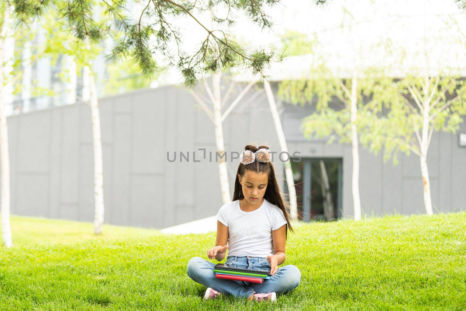 Little girl reading a book in the spring park.