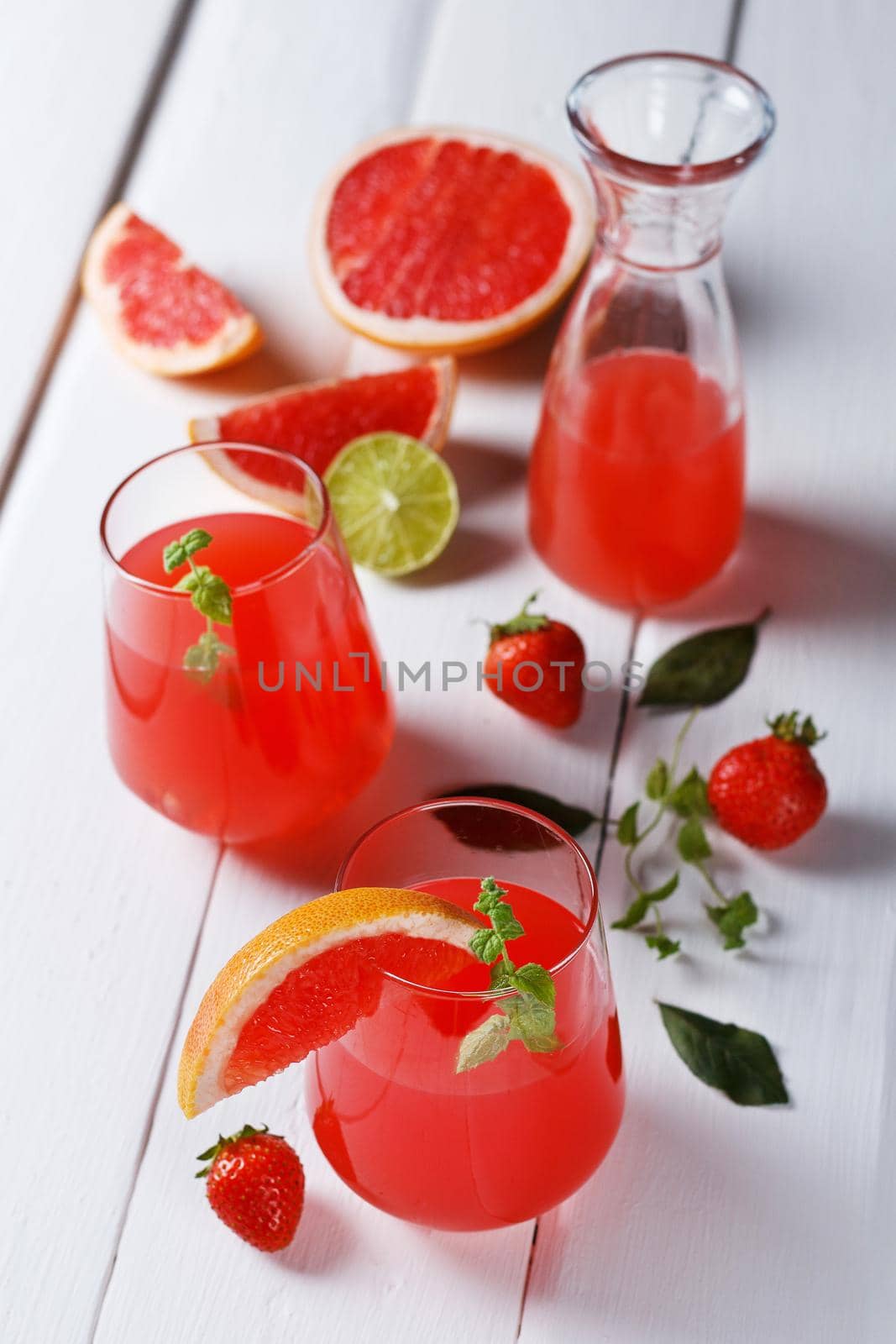 Fresh grapefruit juice in a glass with grapefruit pieces, lime and mint on a wooden background. vertical photo,selective focus by lara29