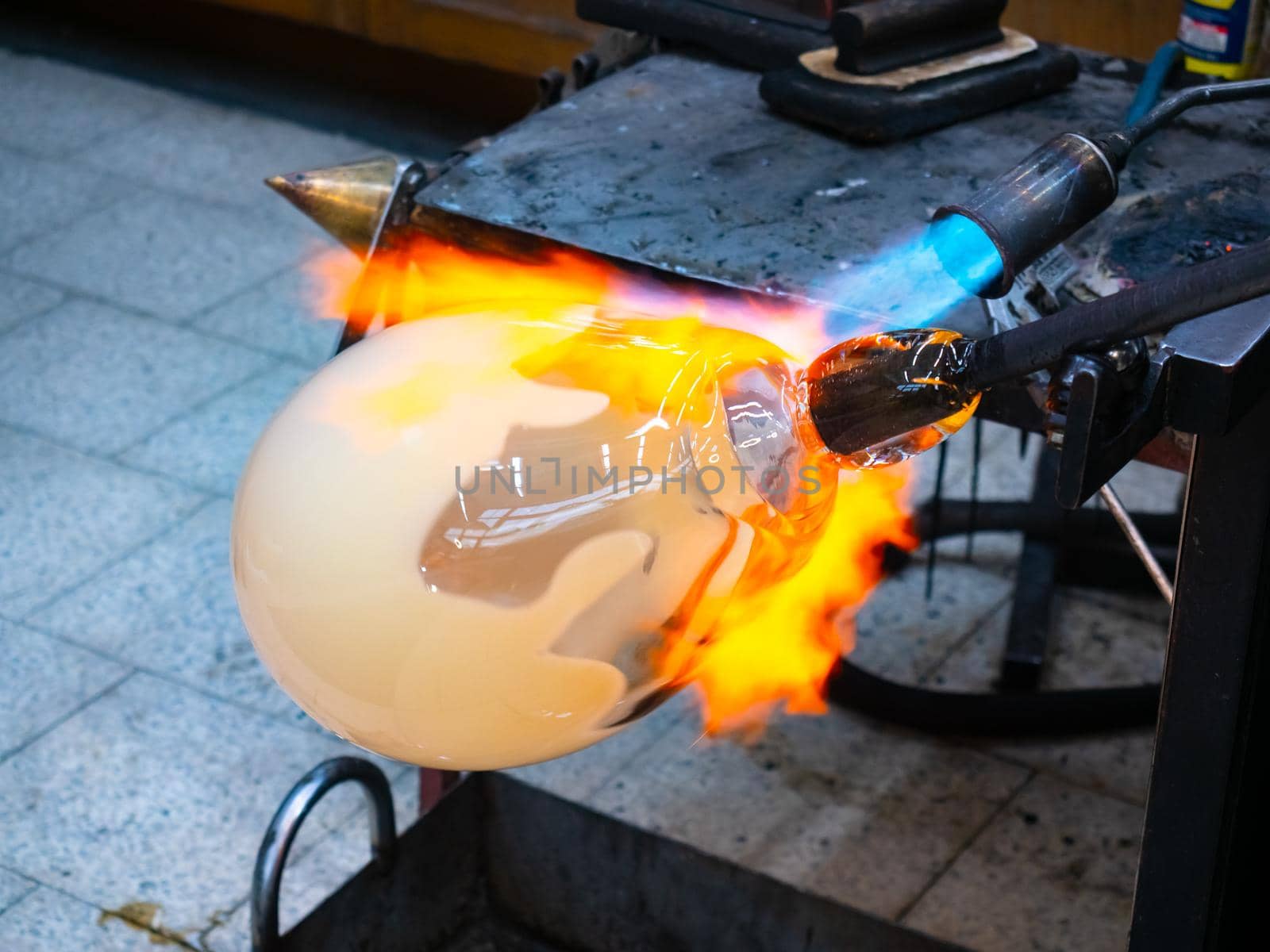 Manual glassblowing process.  Man Working on a big glass art object on pipe with gas torch blue flame 