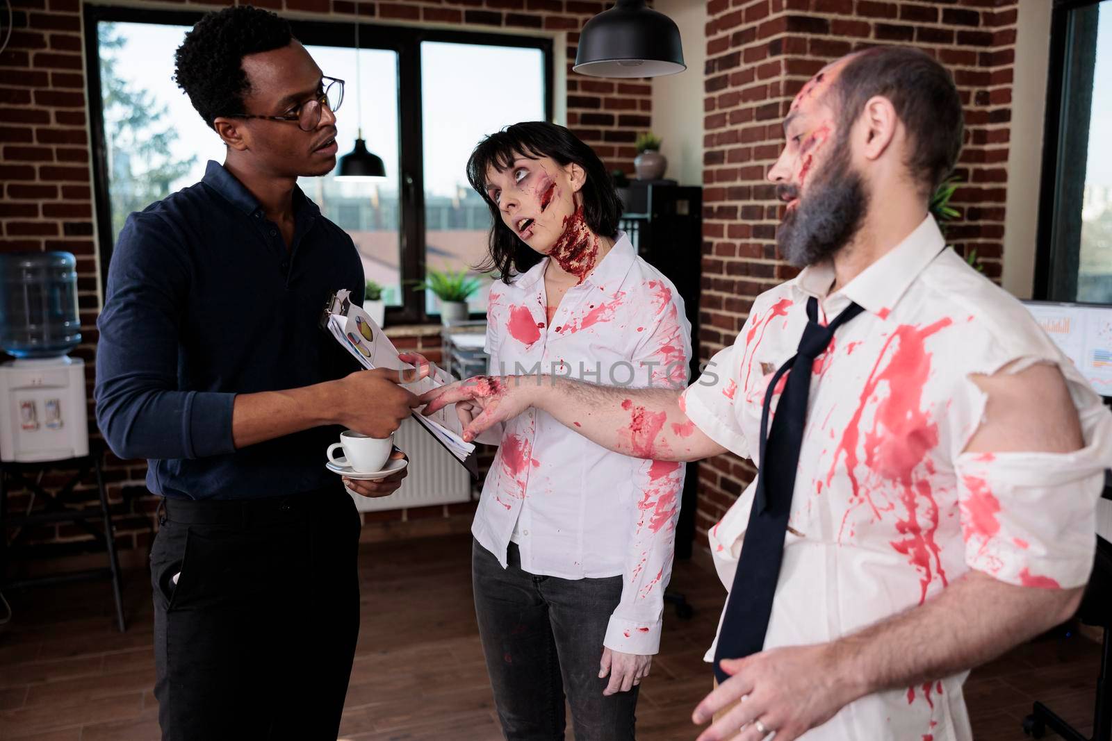 Businessman talking to evil killer zombies in startup office, chatting with brain eating cruel monsters. Man and woman corpses with bloody wounds and scars having conversation with person, macabre.