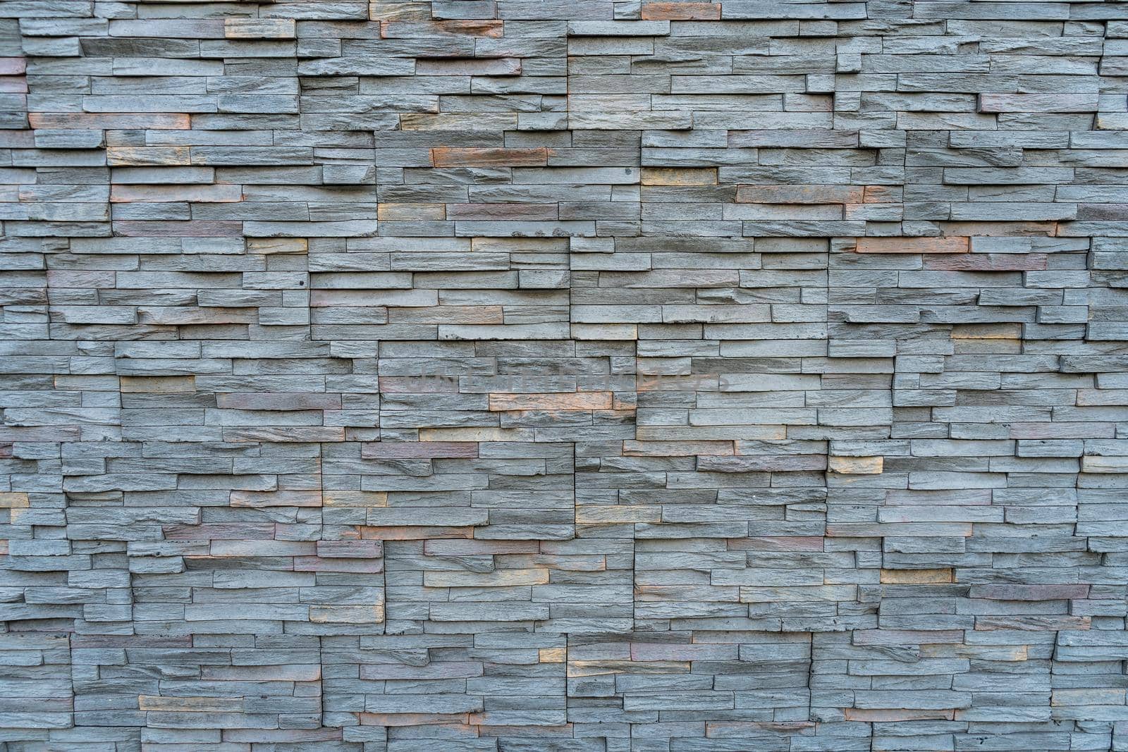 A Background arrangement of stones or slabs of different shapes and colors on a wall.