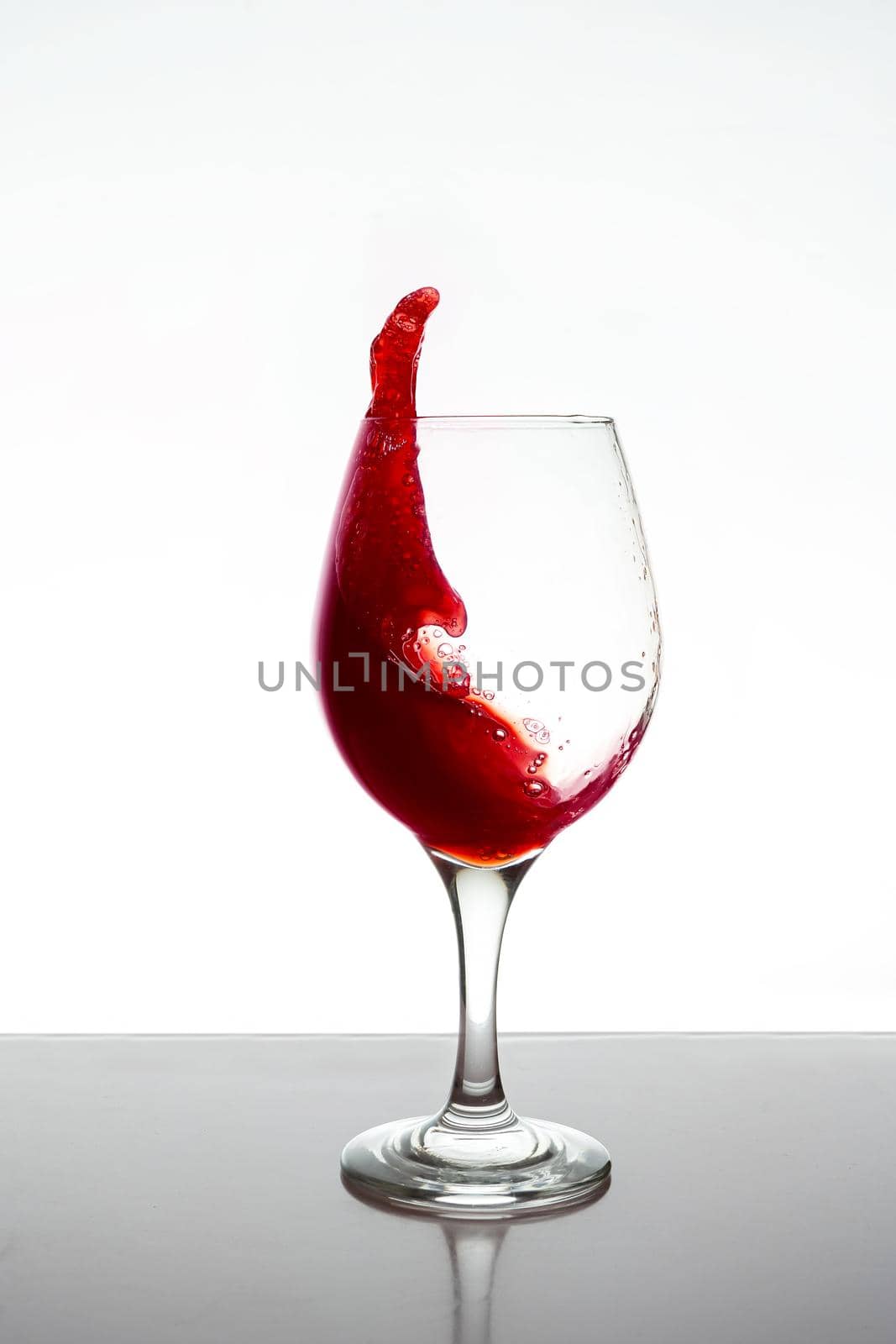 Glass of red wine splashing isolated. by hdcaputo