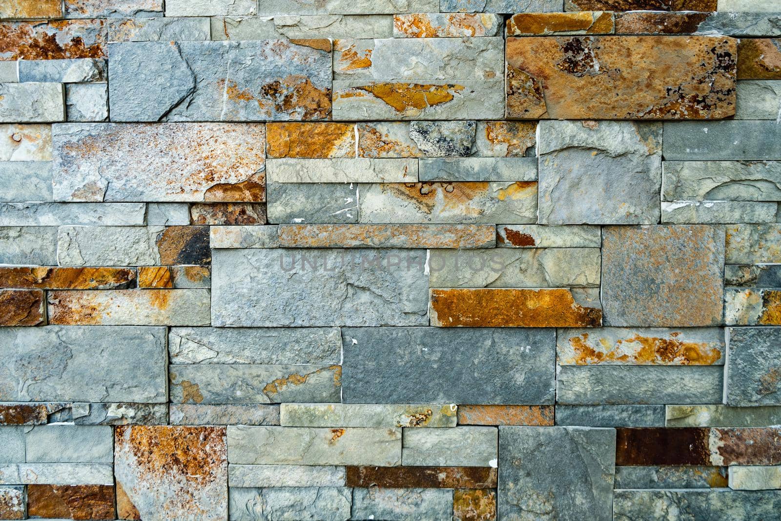 A Background arrangement of stones or slabs of different shapes and colors on a wall.