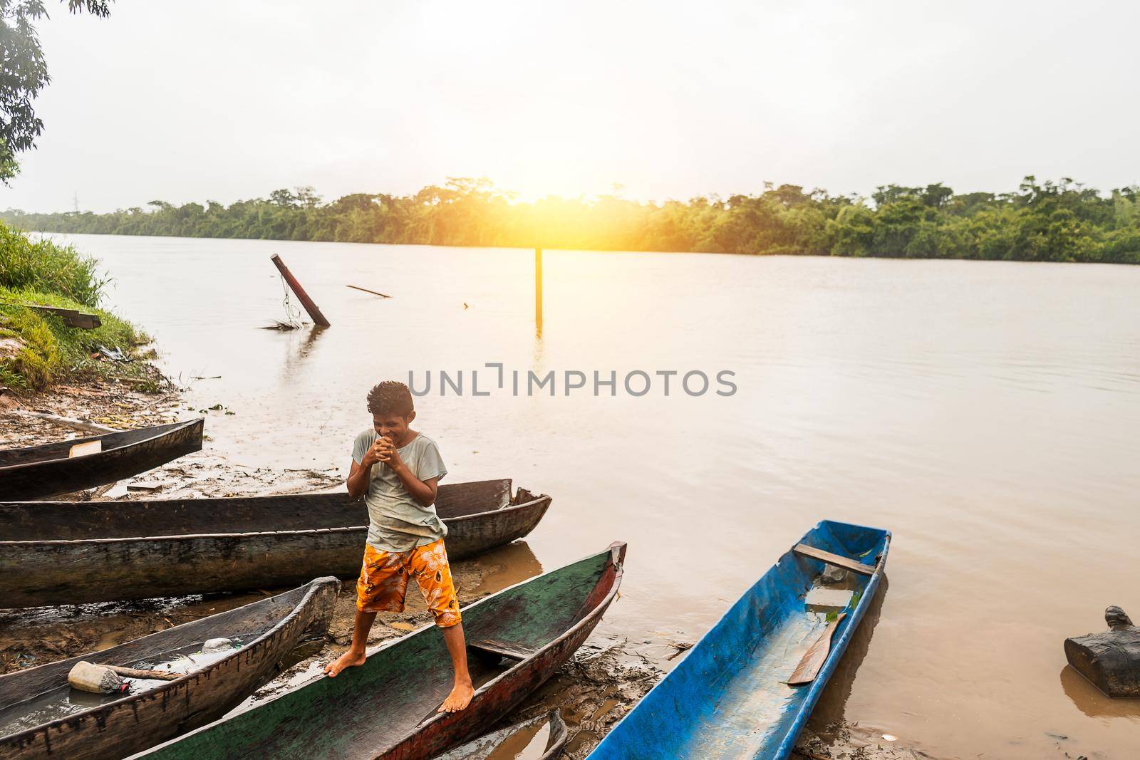 Indigenous boy standing on wooden barges known as cayuco in the northern caribbean of Nicaragua