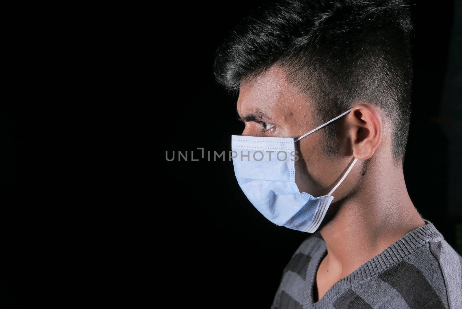 side view of young man with protective mask isolated on black .