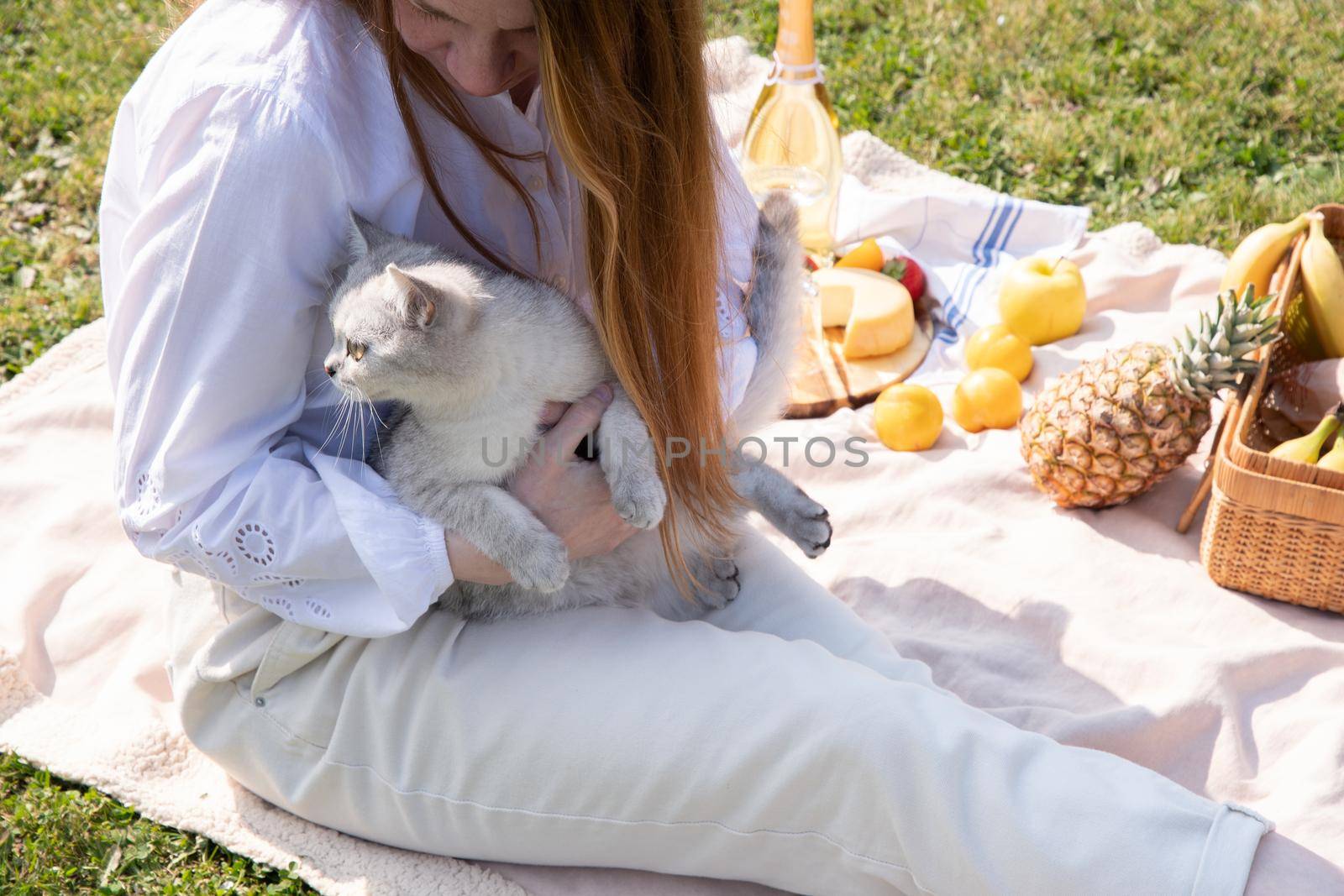 a young woman in a white shirt is resting on a picnic with her pet kitten, by KaterinaDalemans