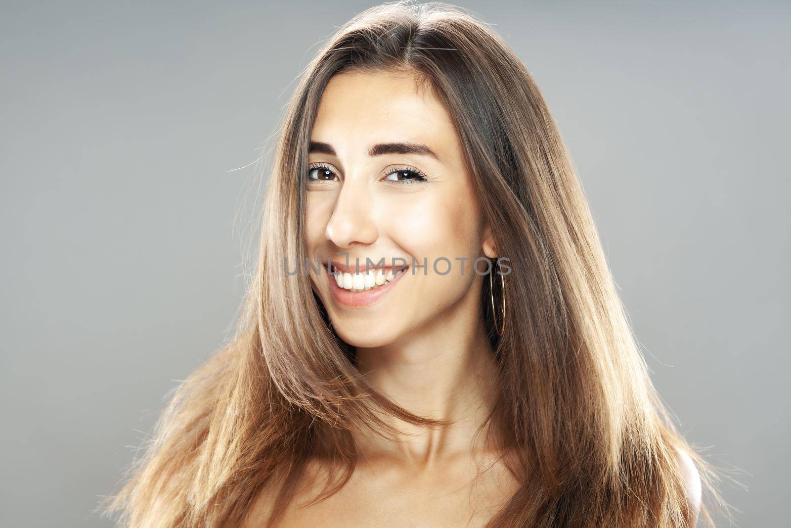 Beautiful brunette girl with hair in the air, studio portrait. Happy smiling face expression. by kokimk