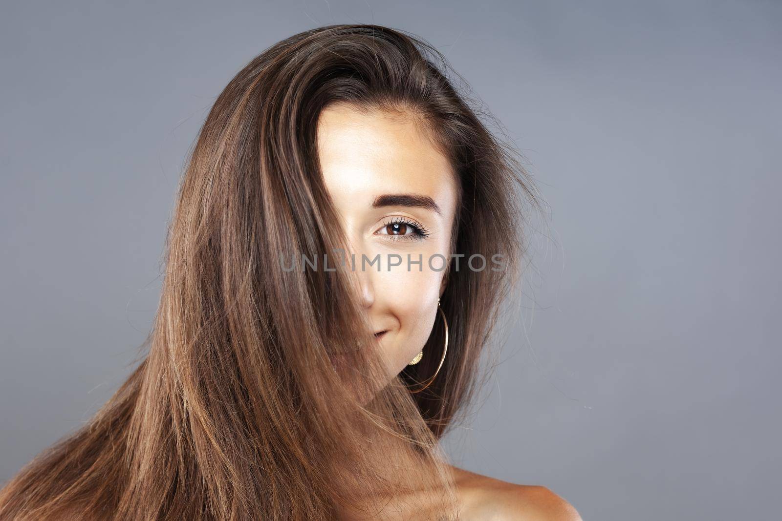 Beautiful brunette girl with hair in the air, studio portrait. Happy smiling face expression. by kokimk