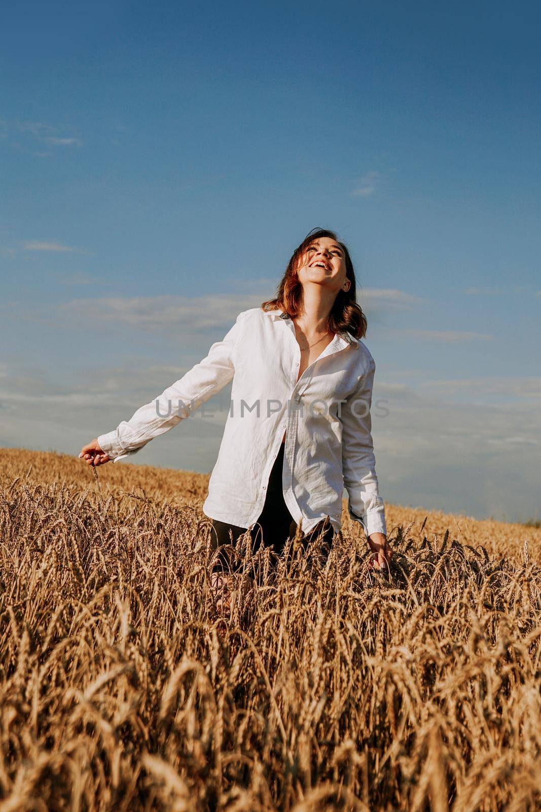 Happy young woman in a white shirt in a wheat field. Sunny day. by natali_brill