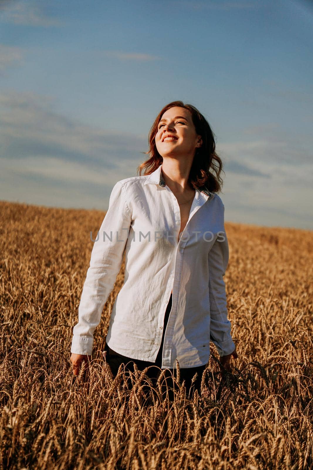 Happy young woman in a white shirt in a wheat field. Sunny day. by natali_brill