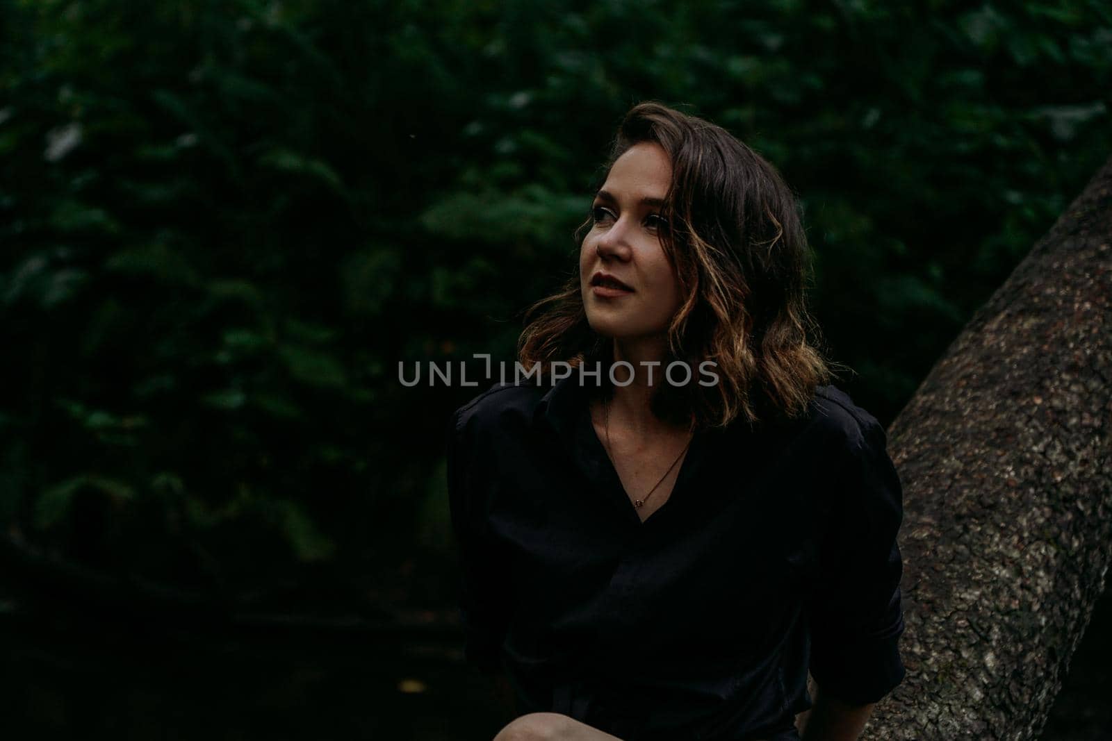 Young woman - close portrait in a dark forest. Woman in black shirt by natali_brill
