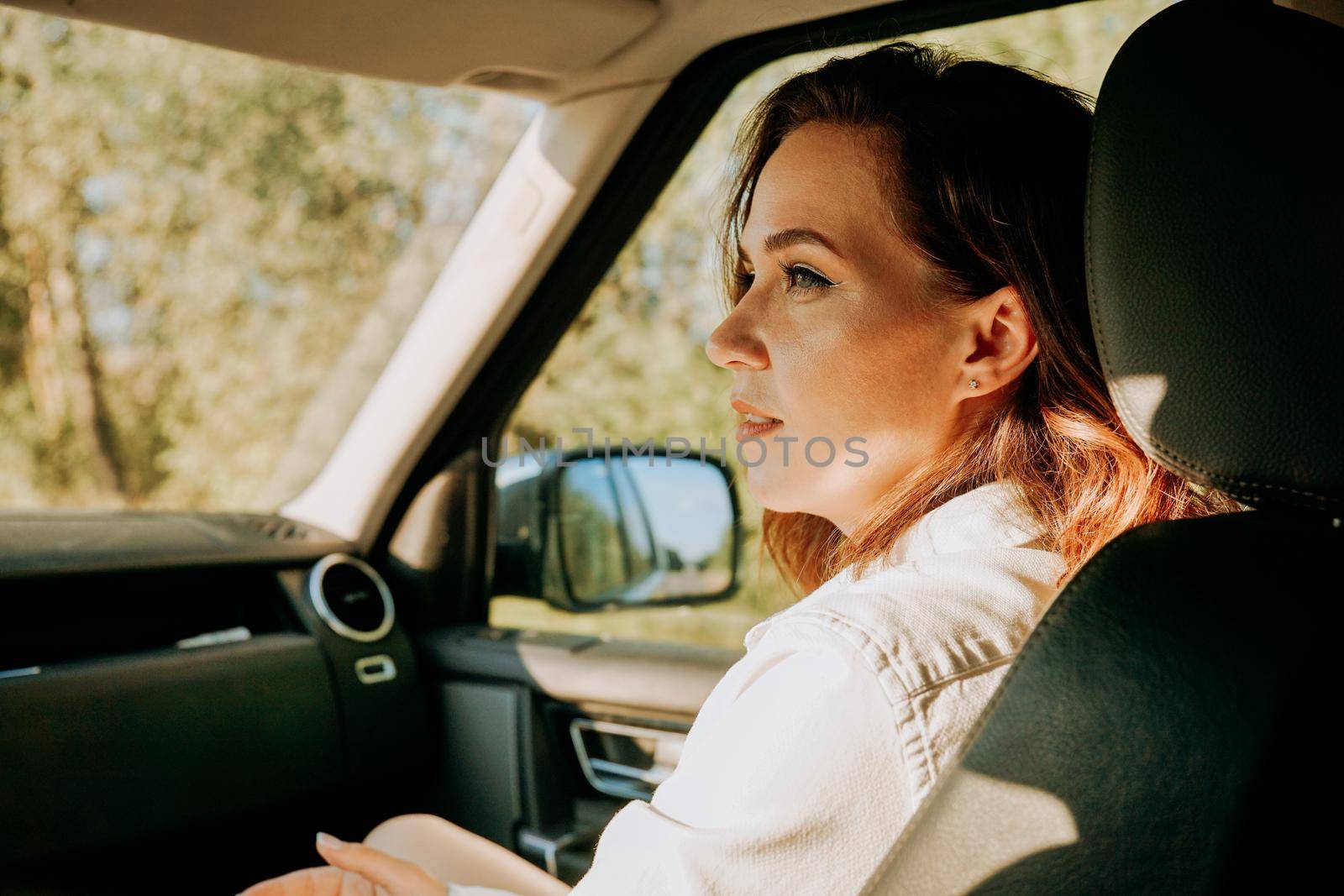 A beautiful young woman in a white shirt in car outside the city by natali_brill