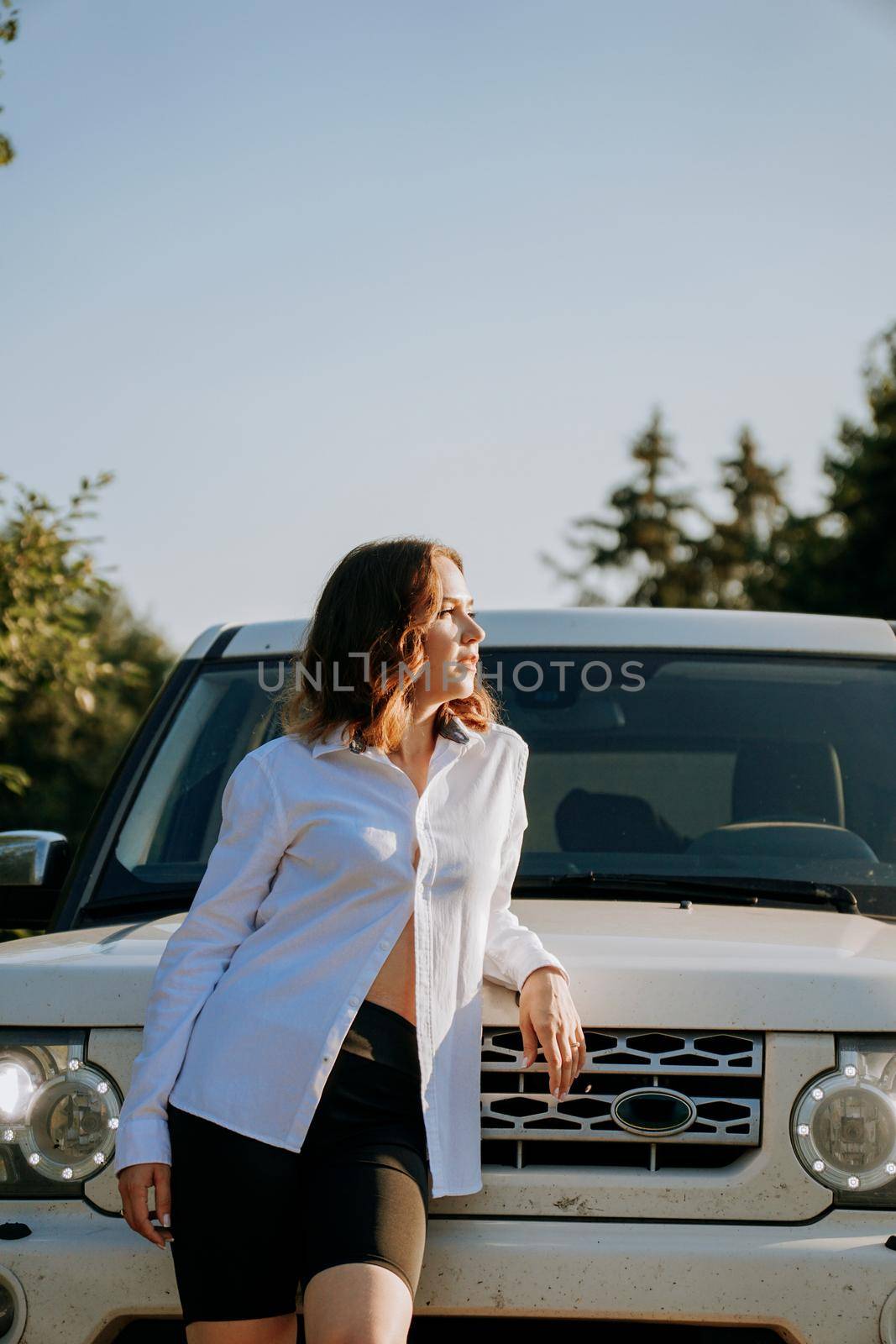 A woman in a white shirt next to a white car on the road by natali_brill
