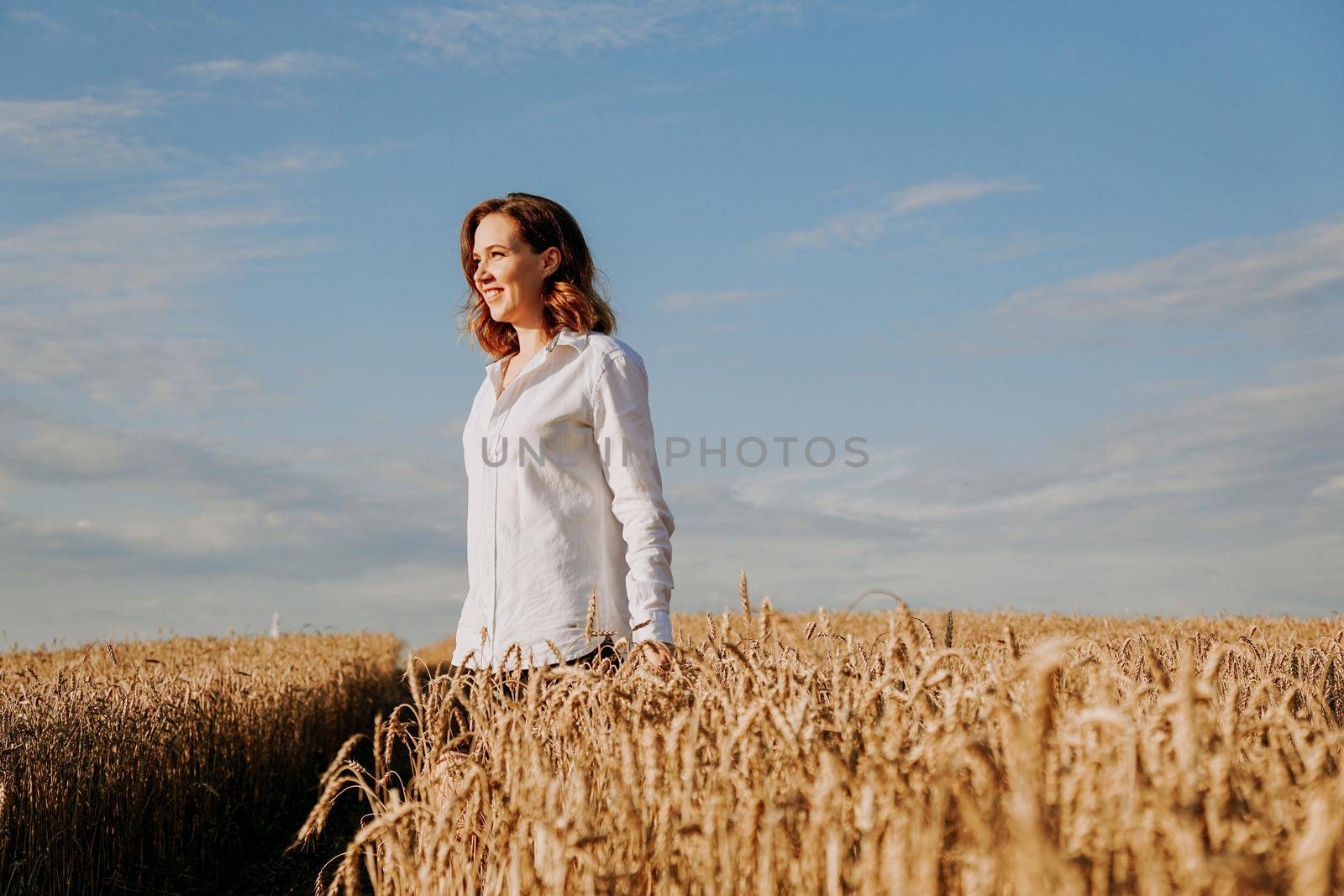 Happy young woman in a white shirt in a wheat field. Sunny day. by natali_brill