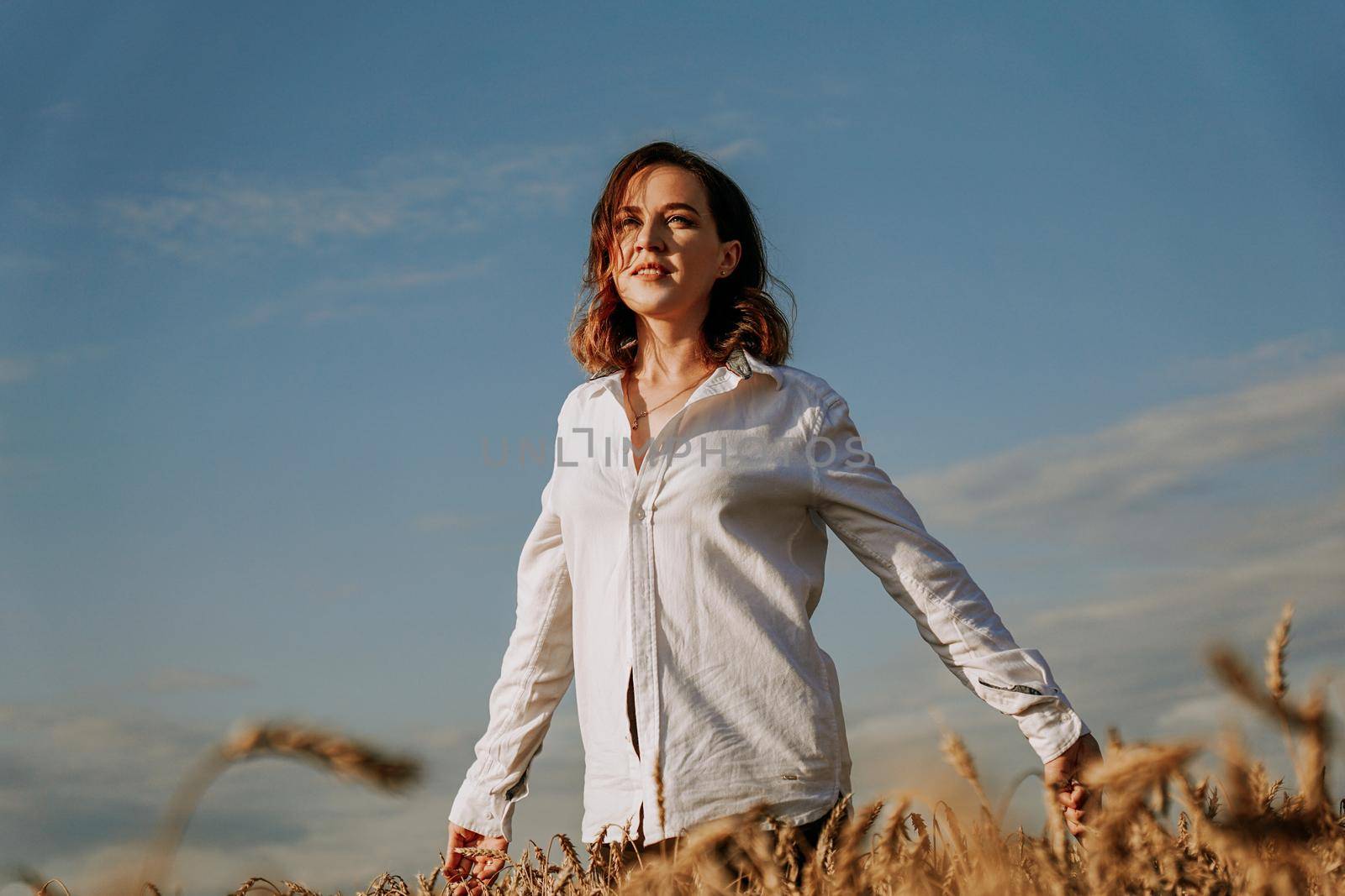 Happy young woman in a white shirt in a wheat field. Sunny day. by natali_brill