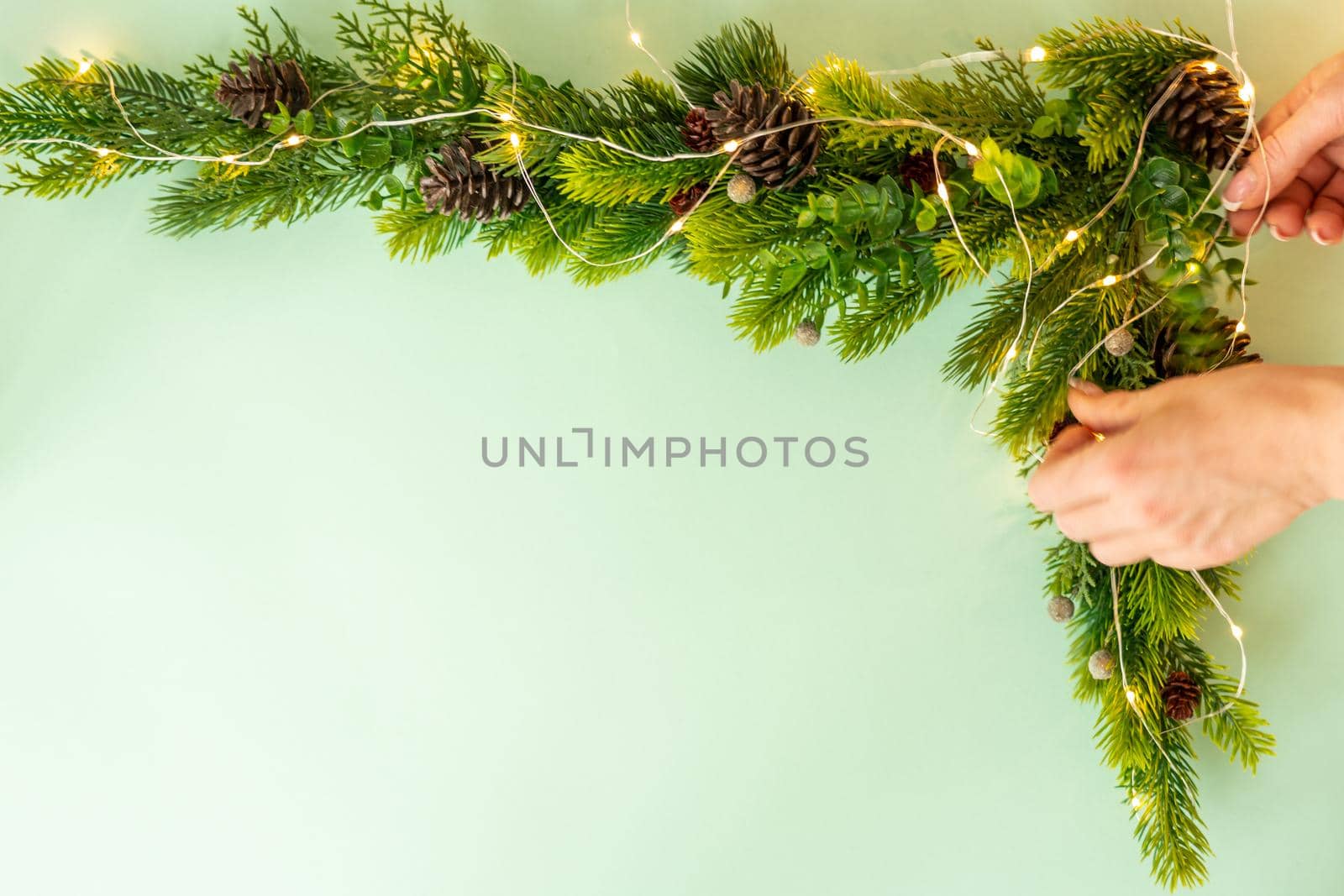 Woman making Christmas tree with corner decoration on green background, flat lay by Mariakray