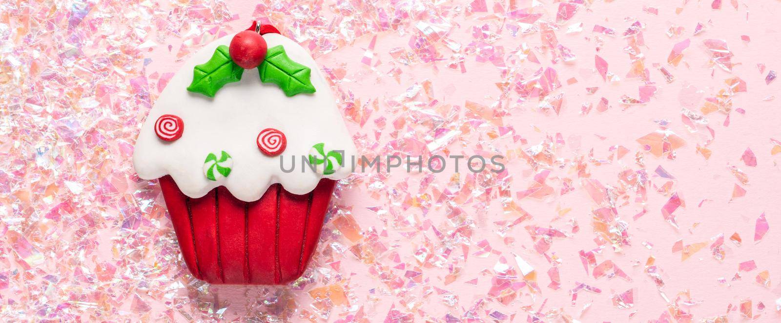 Vintage Plasticine clay cupcake on pink glitter background. Minimal Christmas concept. Happy New Year. Flat lay, top view, copy space by Mariakray