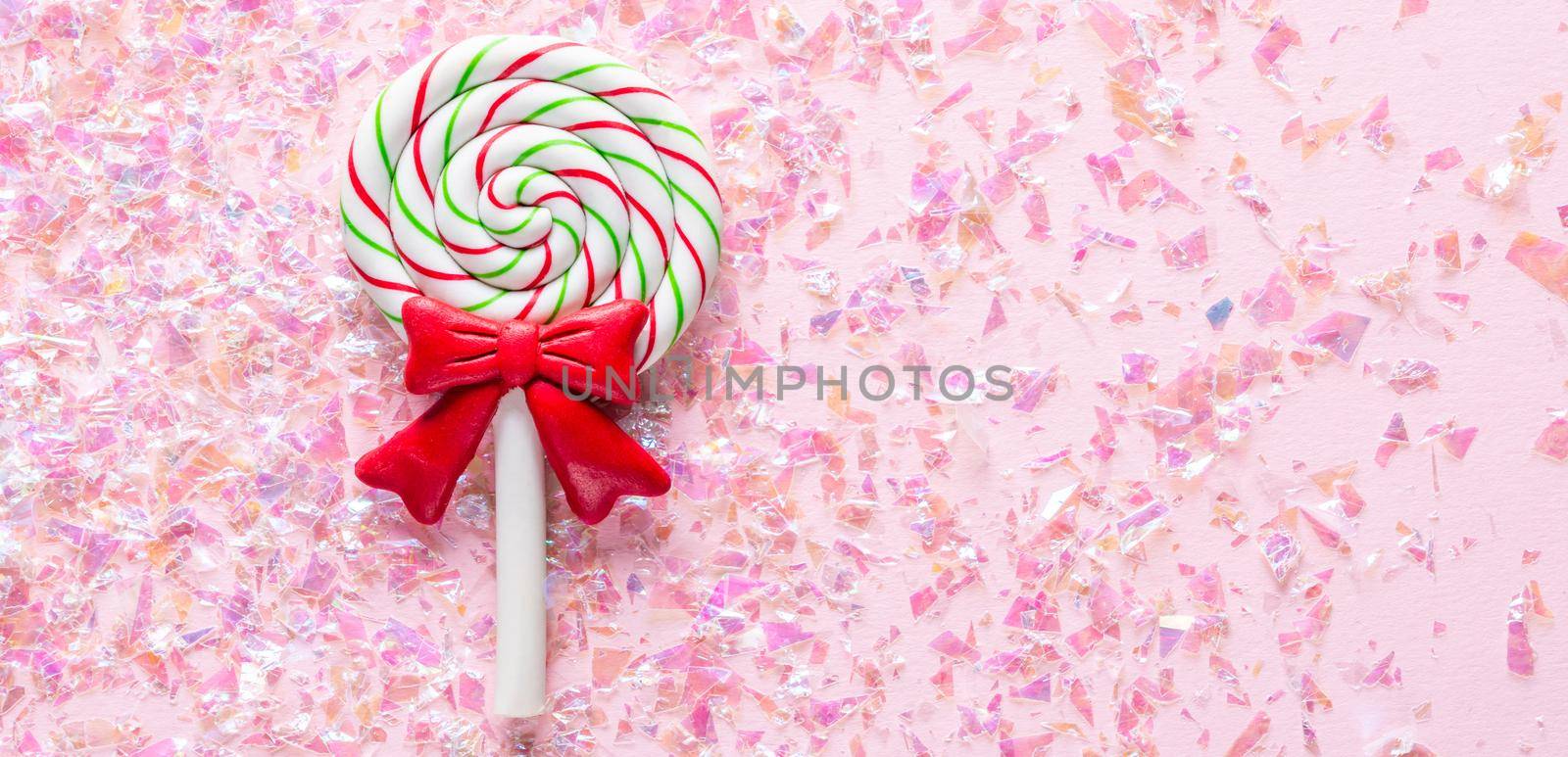 Sweet Lollipop with red bow on pink Background with shiny glitter with copy space by Mariakray
