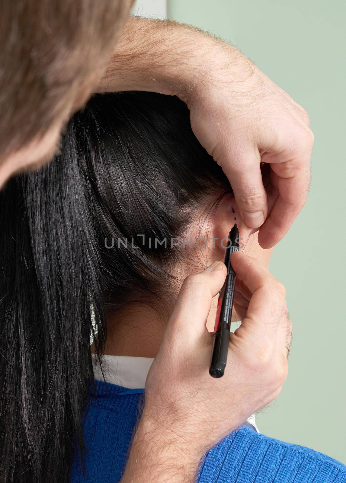 Plastic surgeon examines ear of patient before plastic surgery by Mariakray