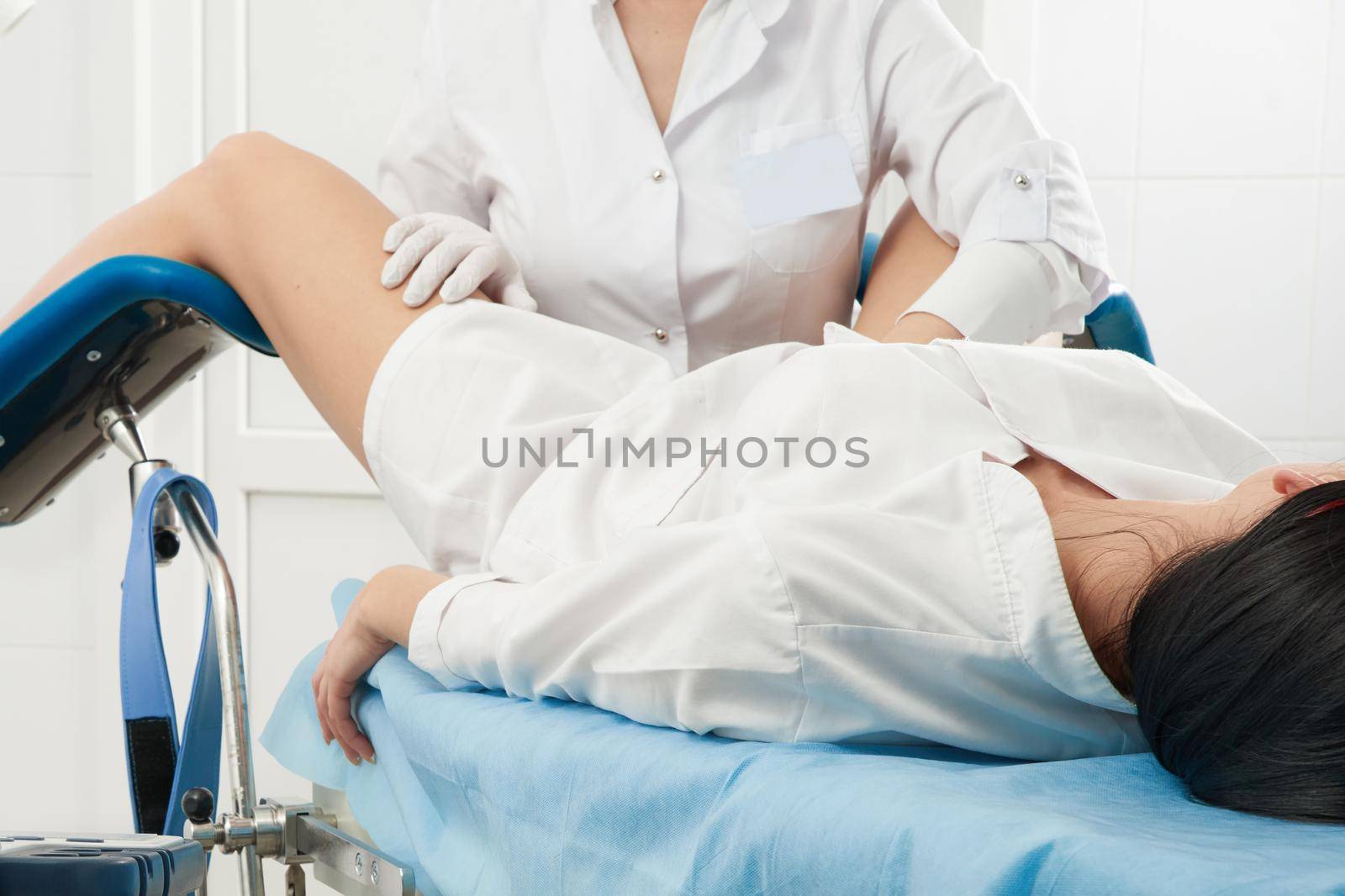 gynecologist is examine a patient who is sitting in a gynecological chair
