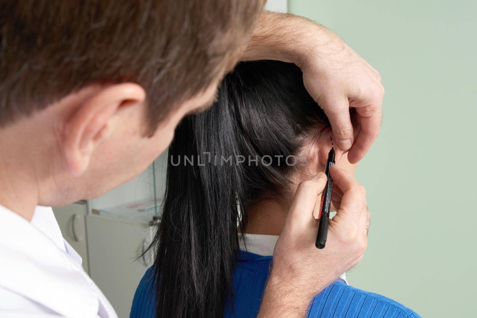 Plastic surgeon examines ear of patient before plastic surgery in hospital
