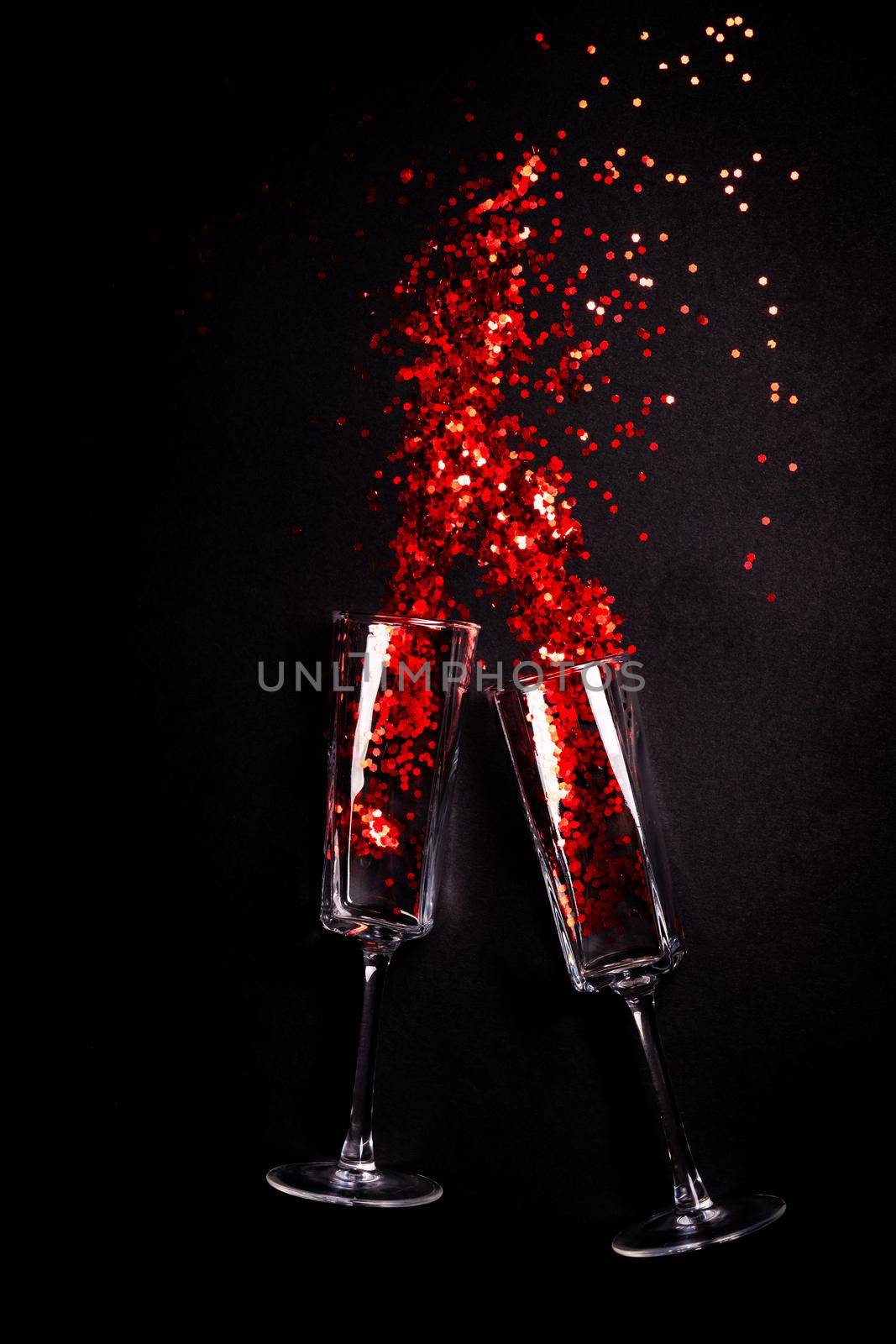 Two Glasses with red confetti on black background, flat lay top view by Mariakray
