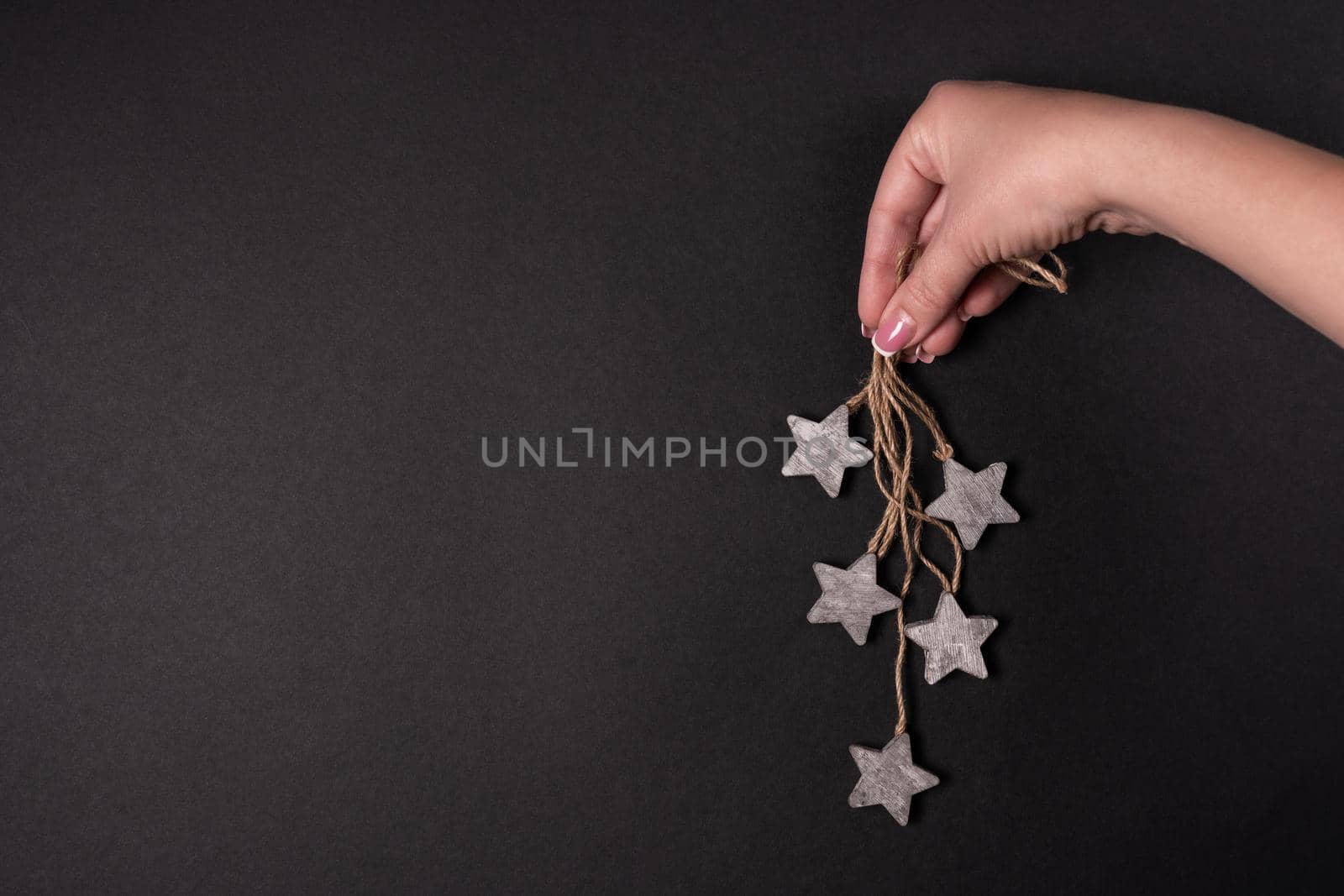 Female hand holding wooden stars with rope, flat lay