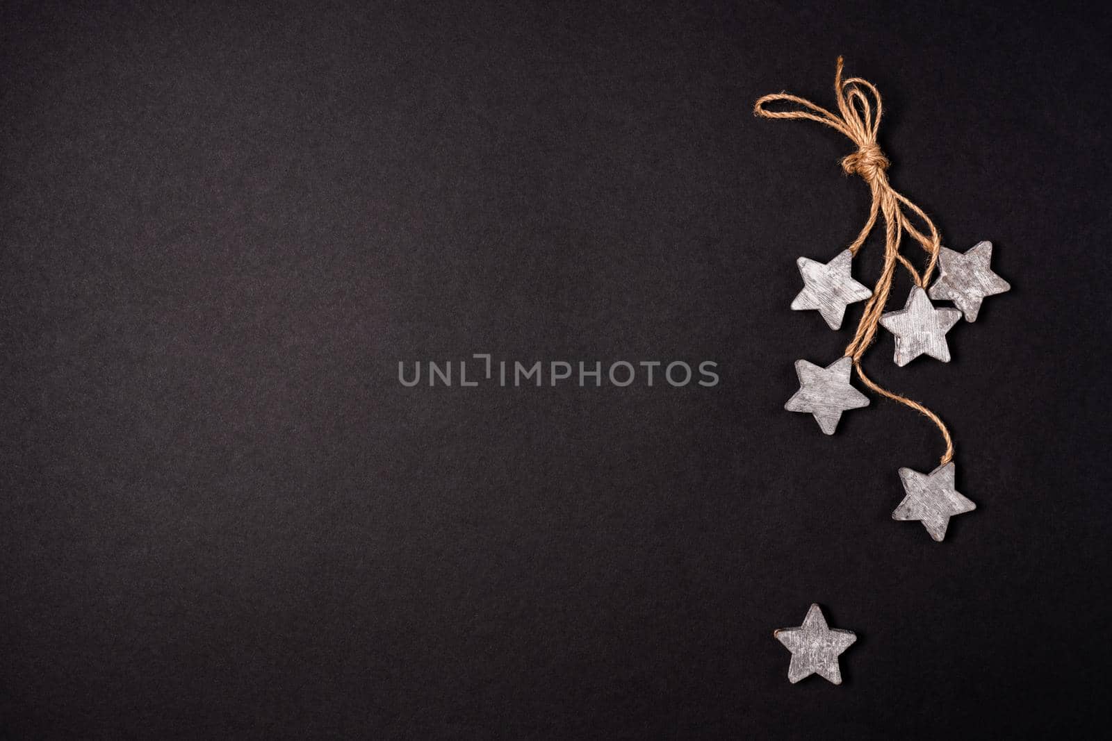 Flat lay decor with wooden stars and rope over black background, top view