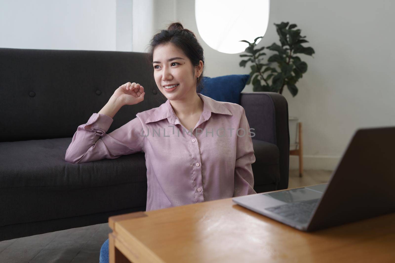 Asian woman using laptop and sitting on sofa at home office.