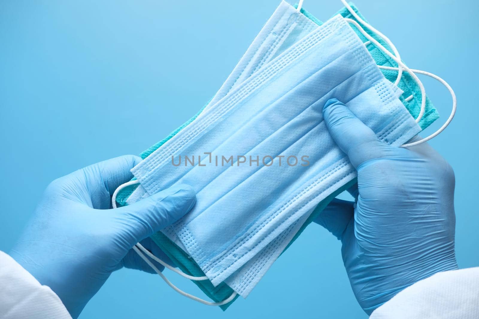 doctor hand in medical glove holding protective surgical face mask, close up .