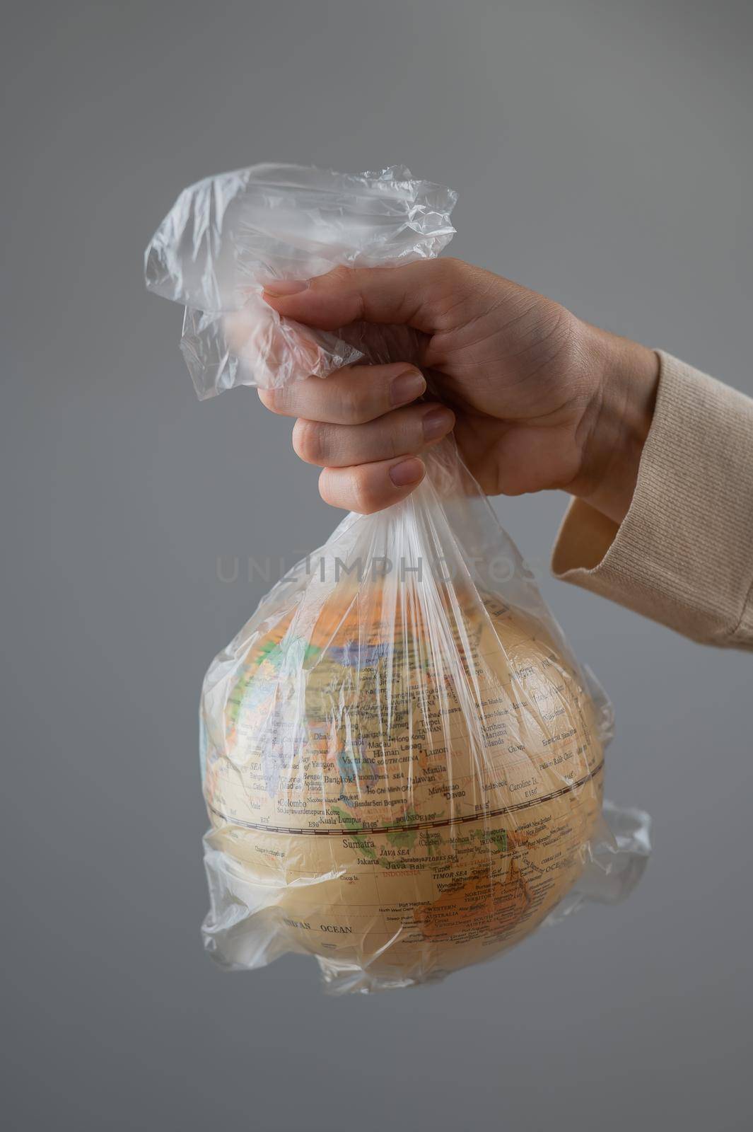 A woman is holding a globe in a plastic bag on a white background