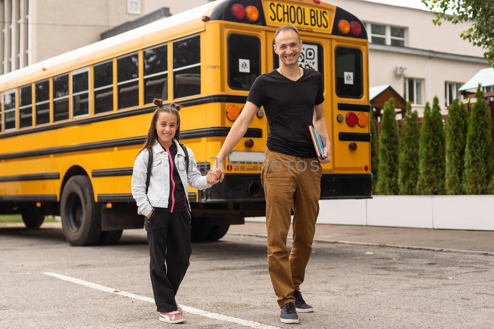 first day at school. father leads a little child school girl in first grade