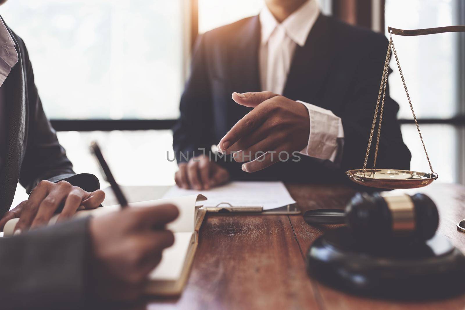 Business woman and lawyers discussing contract papers with brass scale on wooden desk in office. Law, legal services, advice, Justice concept by itchaznong