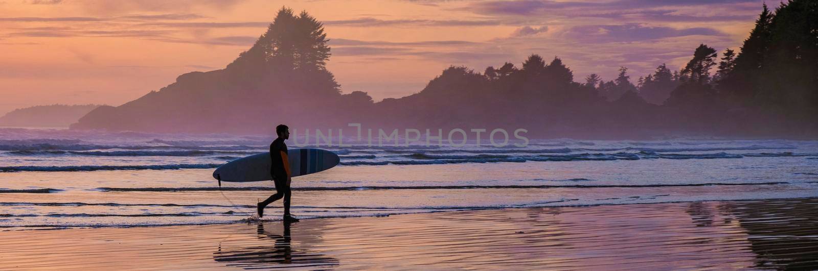 Tofino Vancouver Island Pacific rim coast, surfers with board during sunset at the beach by fokkebok