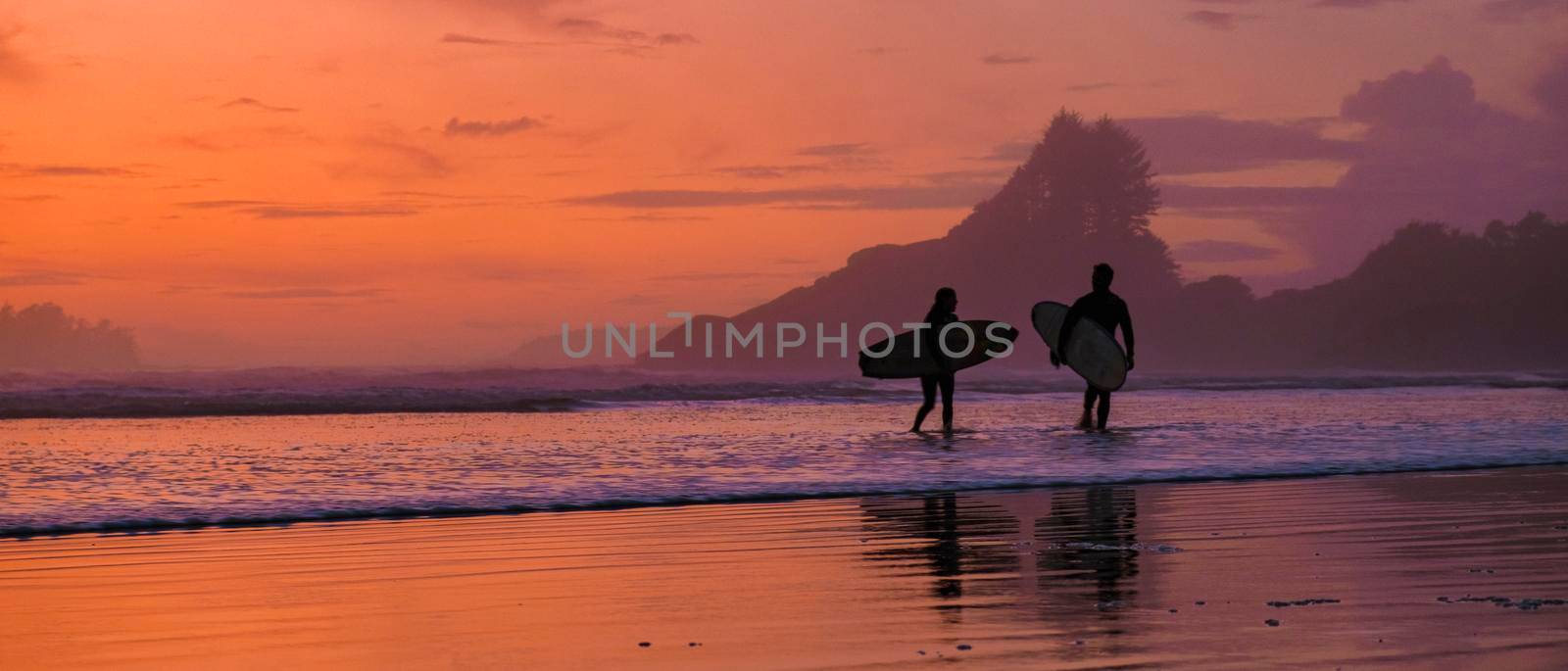 Tofino Vancouver Island Pacific rim coast, surfers with board during sunset at the beach by fokkebok