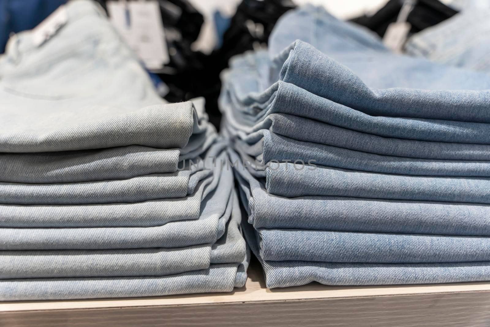 a stack of blue jeans on a shelf in the store. fashion clothing store by audiznam2609