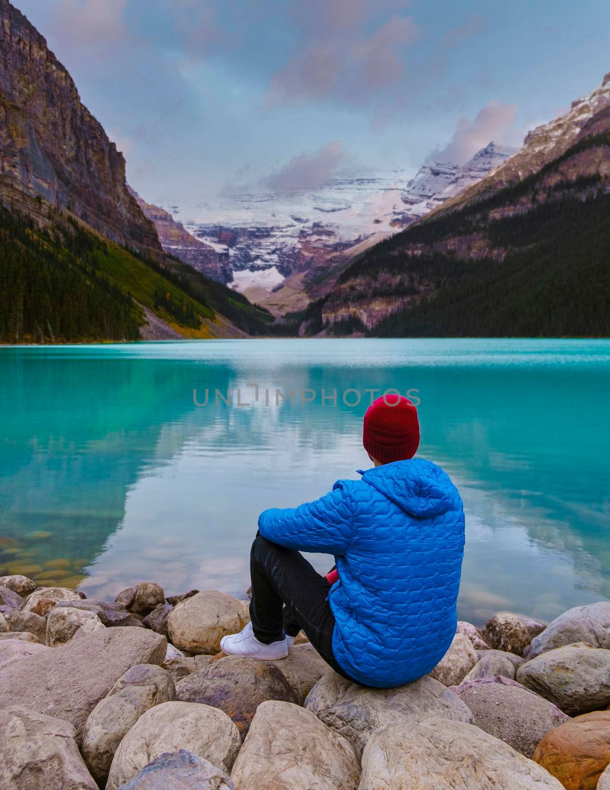 Lake Louise Canadian Rockies Banff national park, Beautiful autumn views of iconic Lake Louise in Banff National Park in the Rocky Mountains of Alberta Canada. young men sitting on a rock by the lake